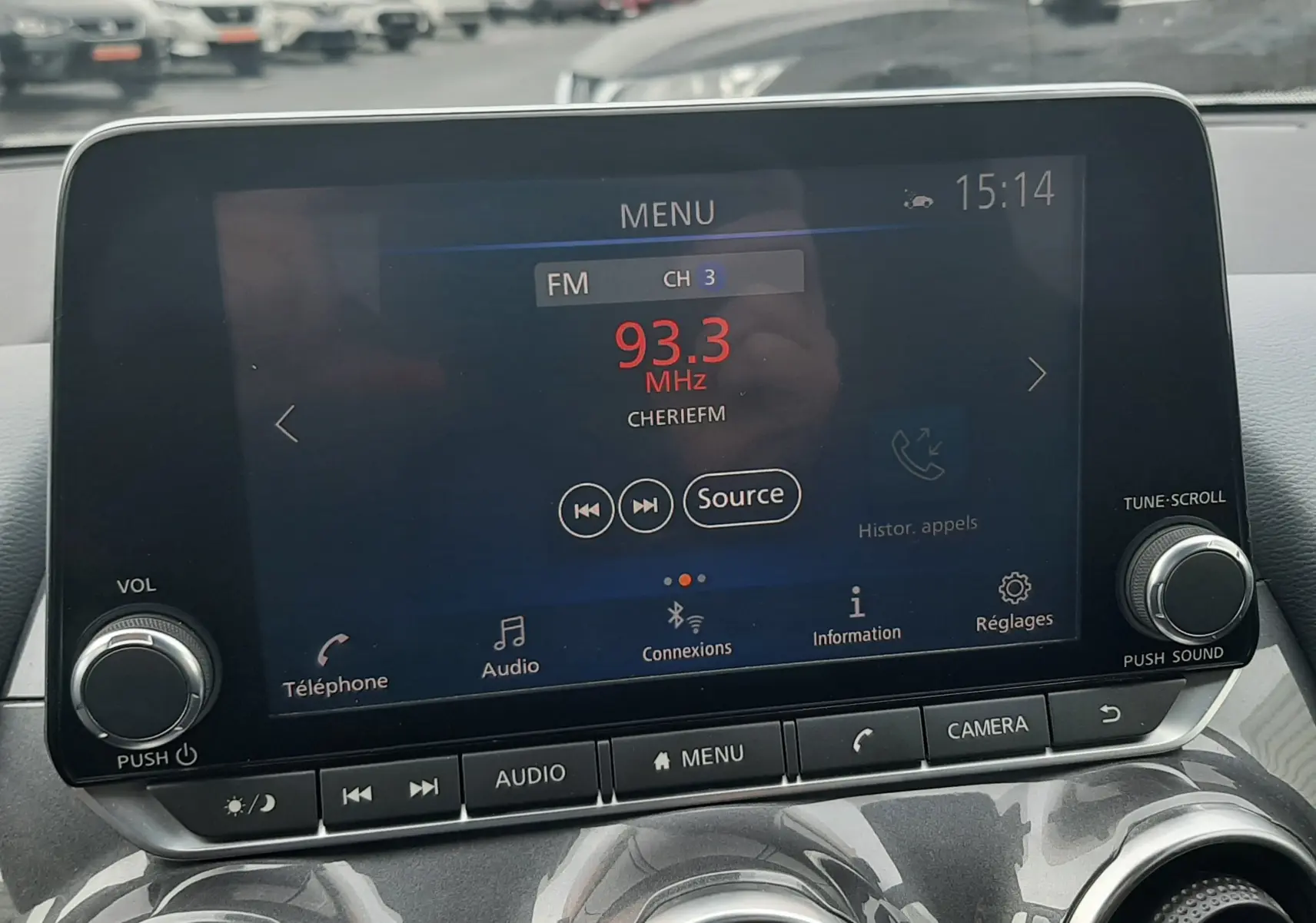 Vue intérieure centrée sur l'écran tactile multimédia du Nissan Juke gris 2020, avec commandes audio et climatisation visibles.