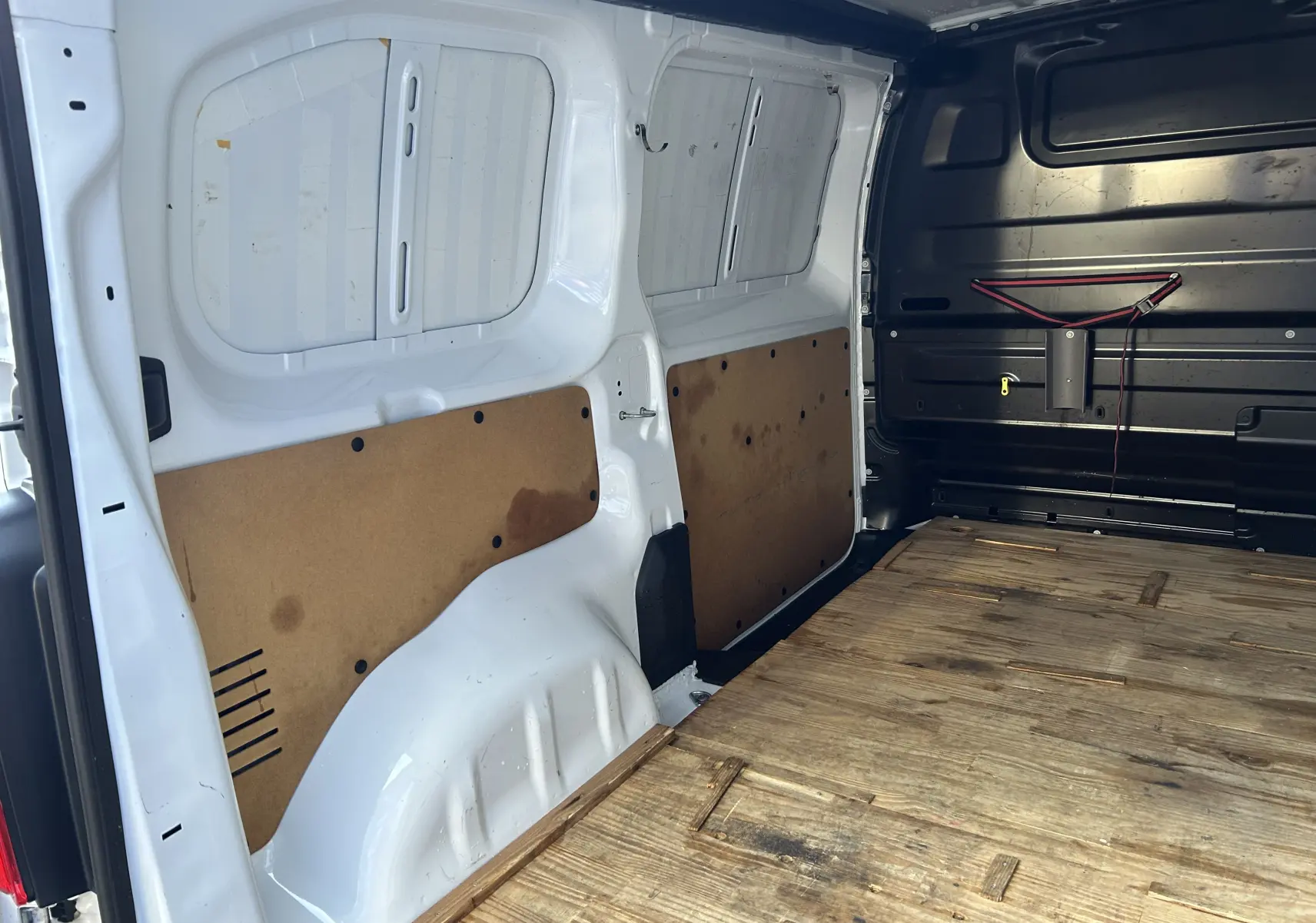 Vue intérieure arrière du fourgon blanc Citroën Jumpy 2017, plancher bois et panneaux latéraux en contreplaqué.