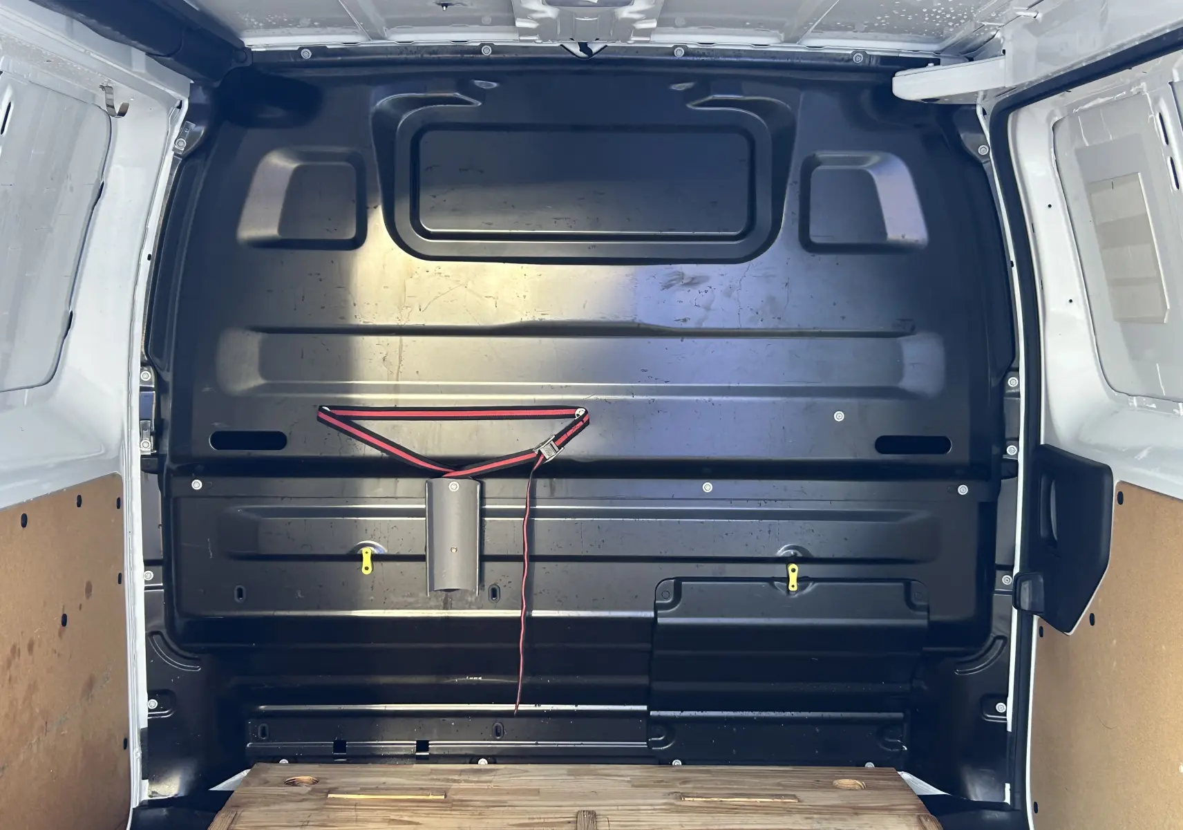 Vue intérieure arrière du fourgon blanc Citroën Jumpy 2017 montrant la cloison noire et le plancher en bois.