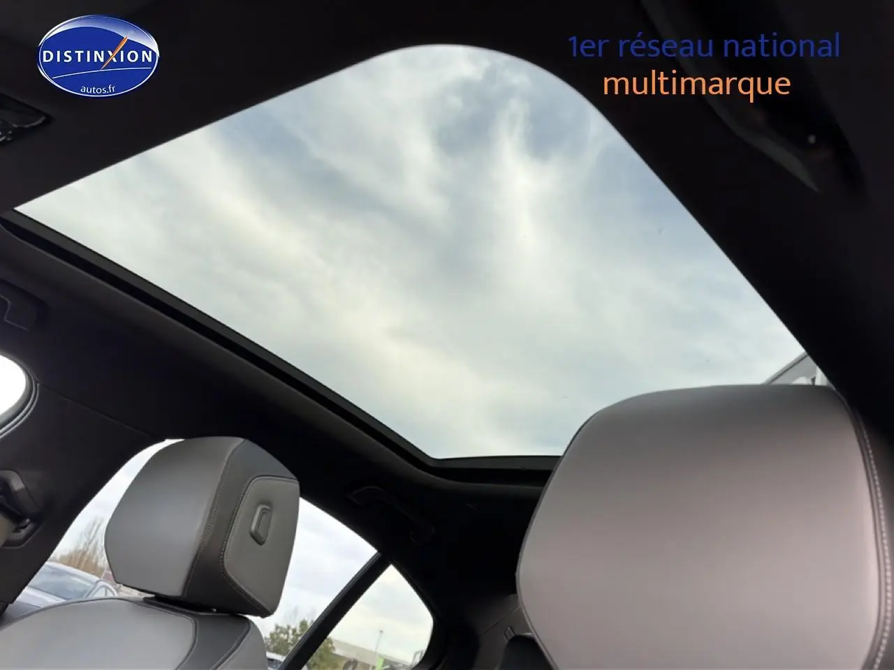 Toit panoramique ouvert avec ciel nuageux visible, intérieur noir et sièges gris clair de la BMW Série 5 i5 M60 2024.