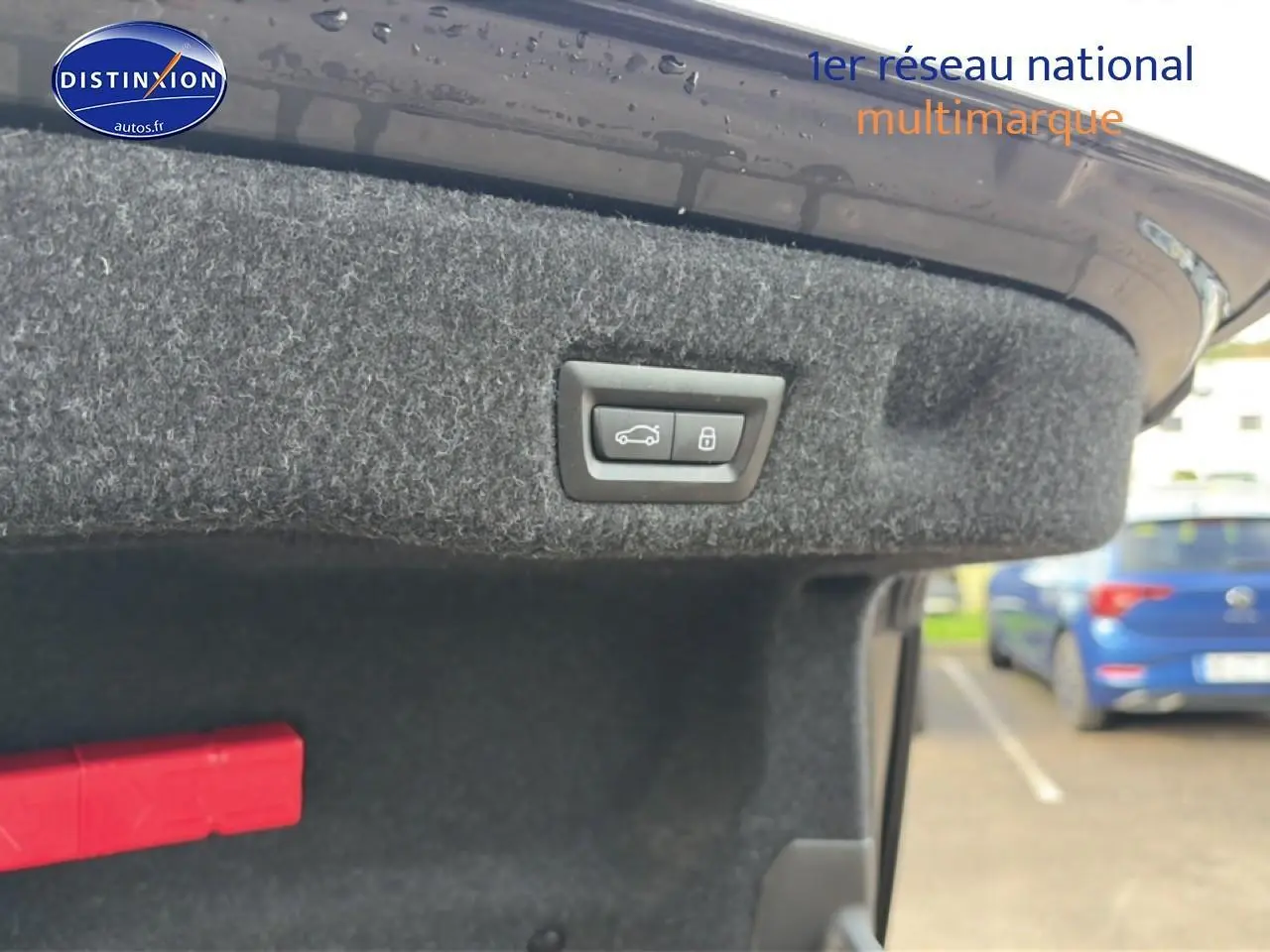 Bouton d'ouverture de coffre sur la partie intérieure du hayon d'une BMW Série 5 noire, vue rapprochée.