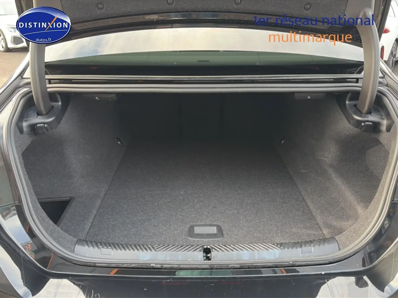 Coffre ouvert vu de l'arrière d'une BMW Série 5 i5 M60 noire, montrant un espace de rangement vide et propre.