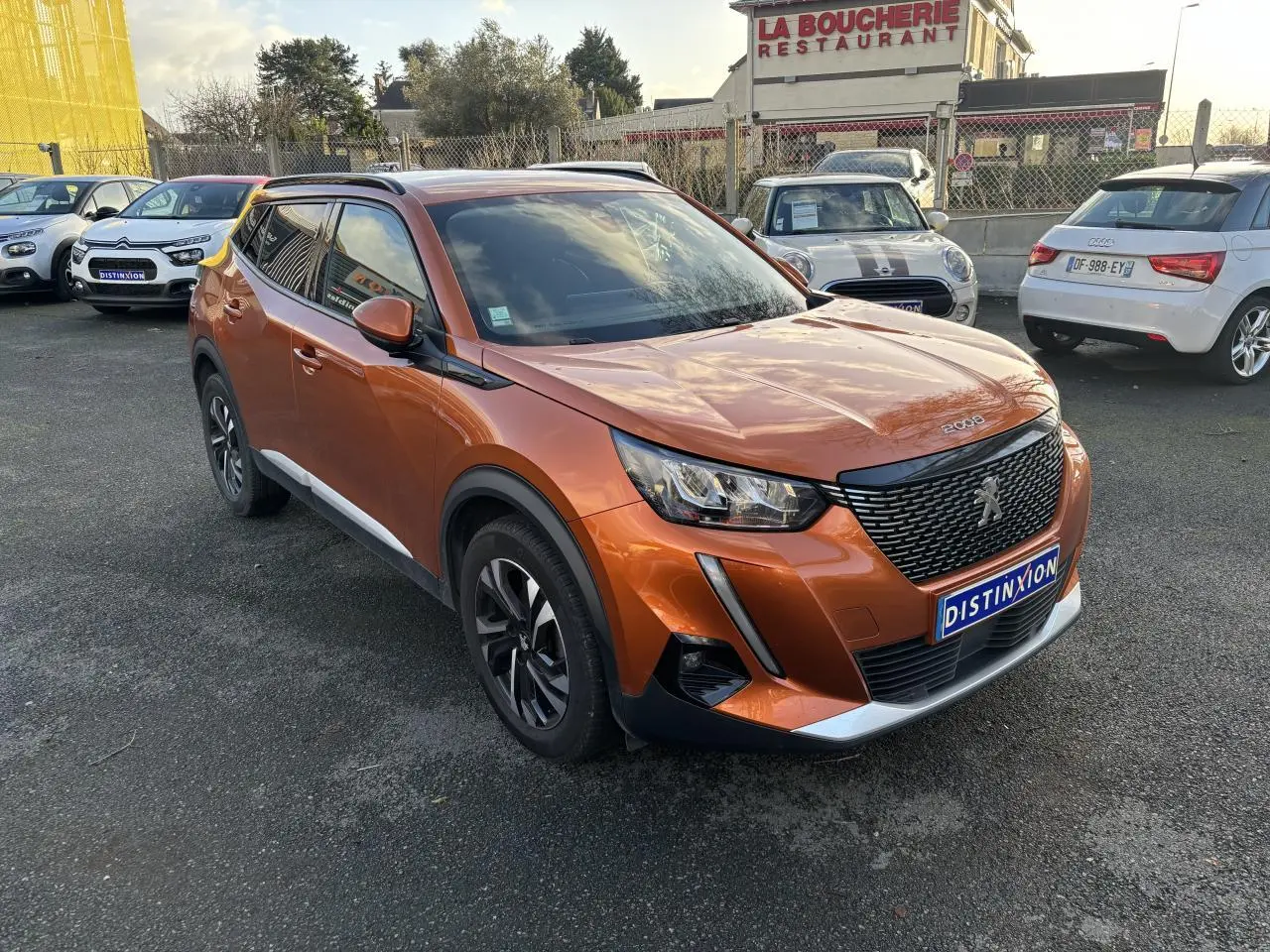 Peugeot 2008 orange fusion vue 3/4 avant droit, avec calandre noire et jantes alliage bicolores.