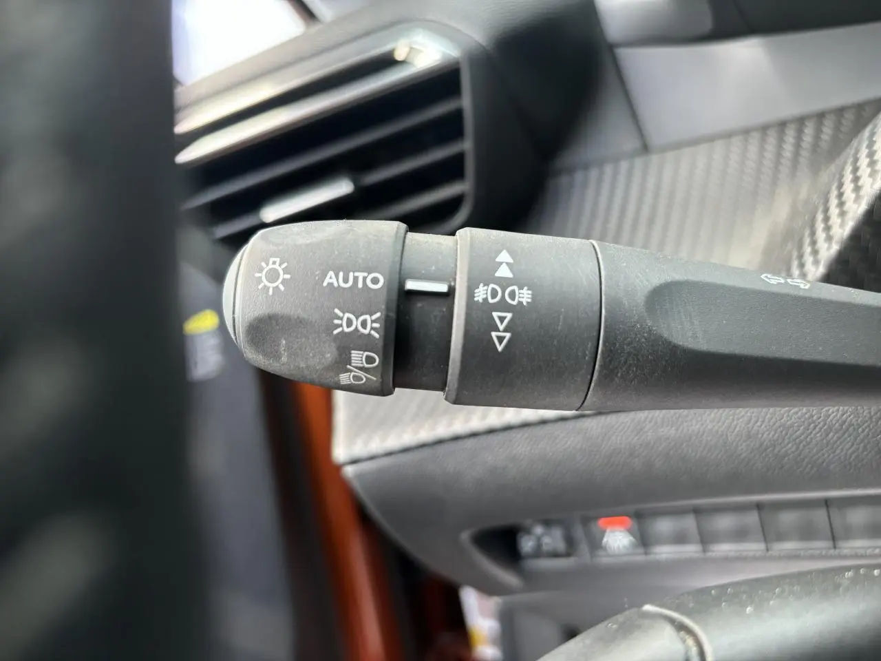 Gros plan sur la commande des phares à gauche du volant dans l’habitacle du Peugeot 2008 Orange Fusion 2021.