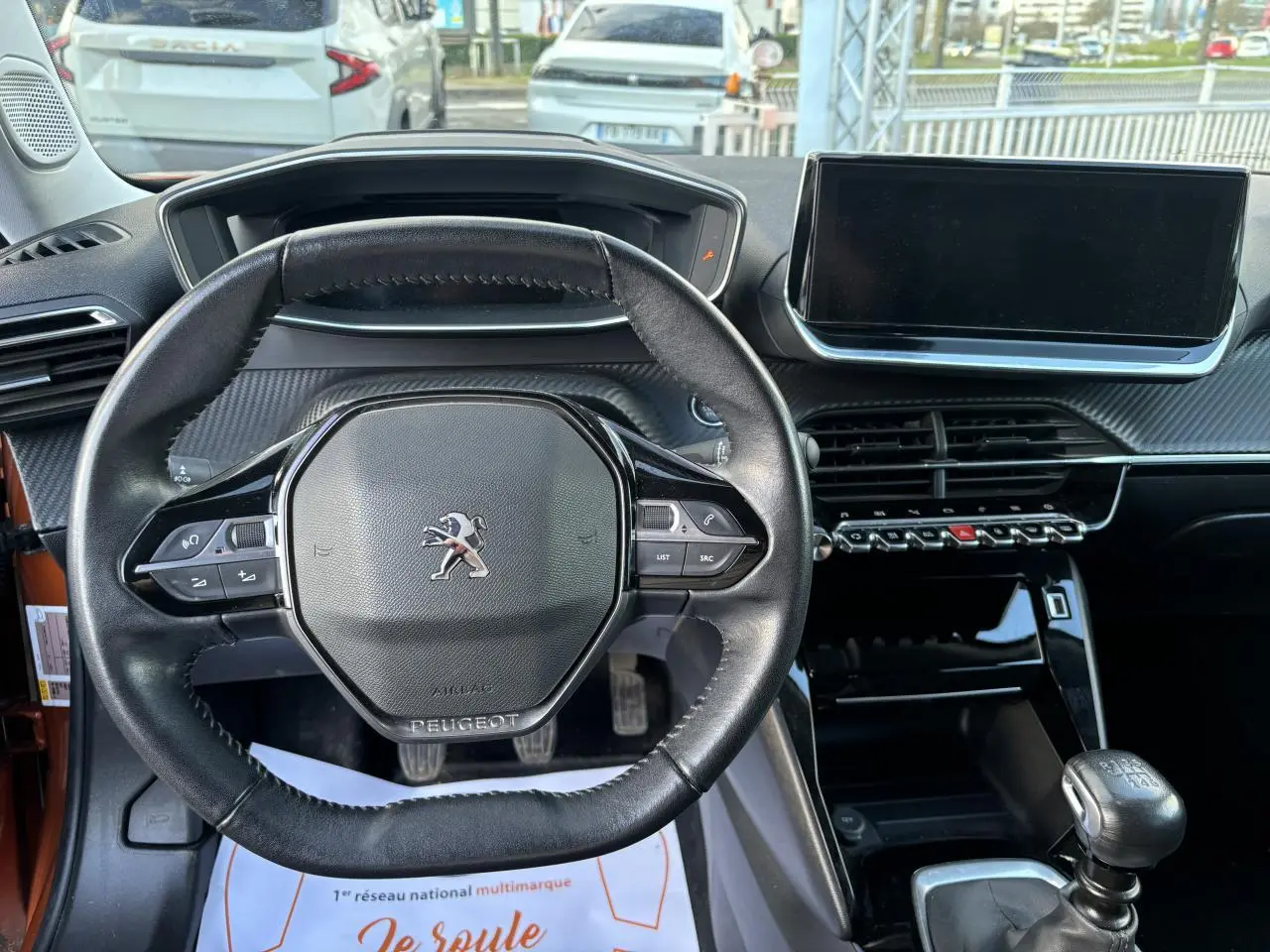 Vue intérieure centrée sur le volant compact cuir du Peugeot 2008 2021 avec écran tactile et levier de vitesse manuel.