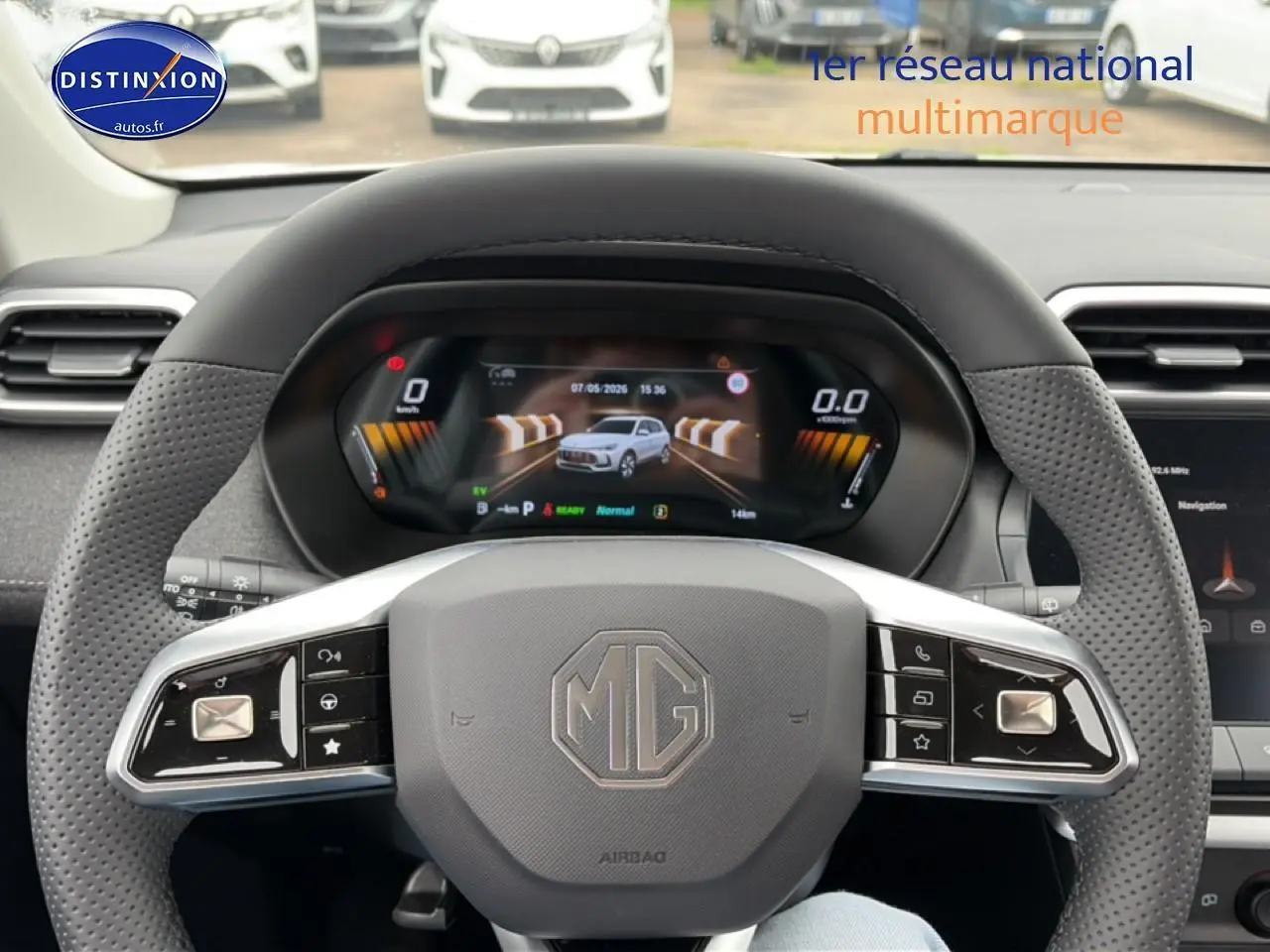 Vue intérieure centrée sur le volant MG d'un MG ZS Hybrid blanc, avec tableau de bord numérique et écran tactile visible.