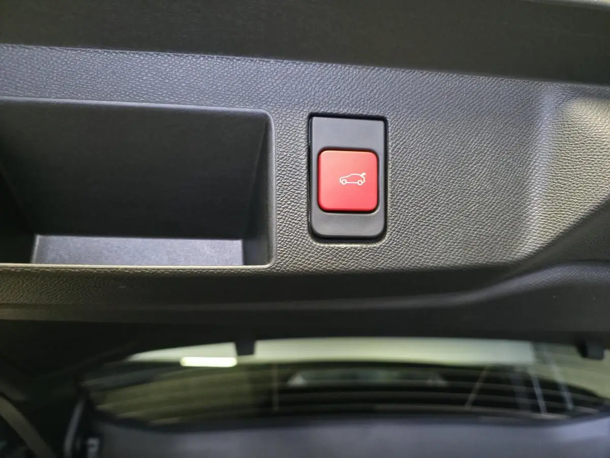 Bouton rouge d'ouverture électrique du hayon sur le panneau intérieur du coffre du Citroën C5 Aircross noir.