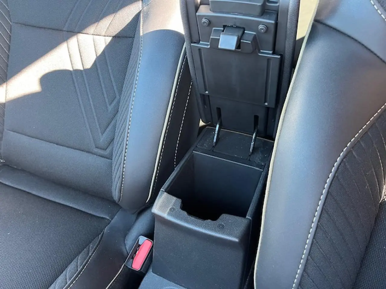 Vue rapprochée de la console centrale noire ouverte entre les sièges avant noirs du Renault Symbioz 2025.