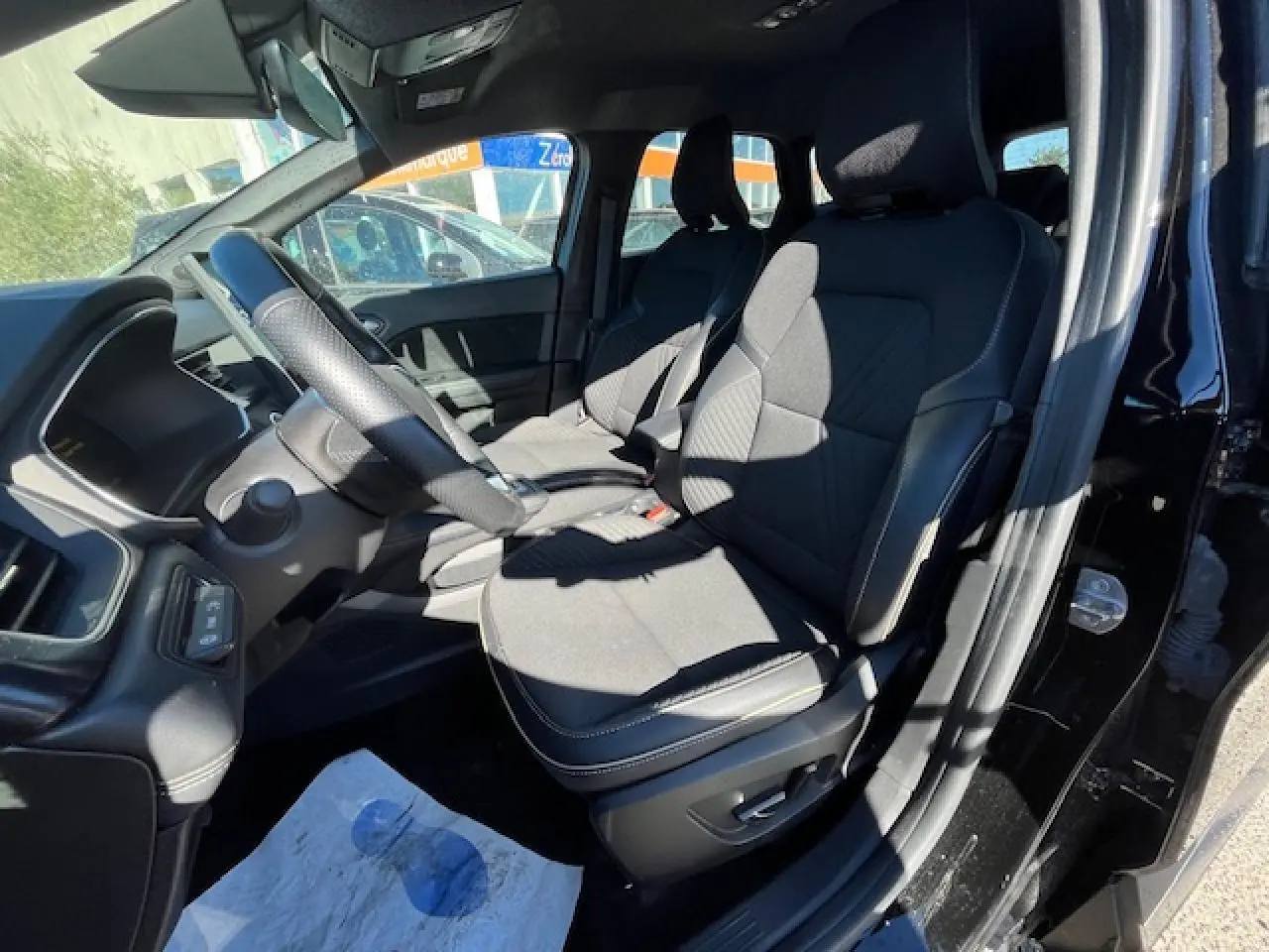 Vue intérieure côté conducteur du Renault SYMBIOZ noir, montrant les sièges avant et le volant avec commandes intégrées.