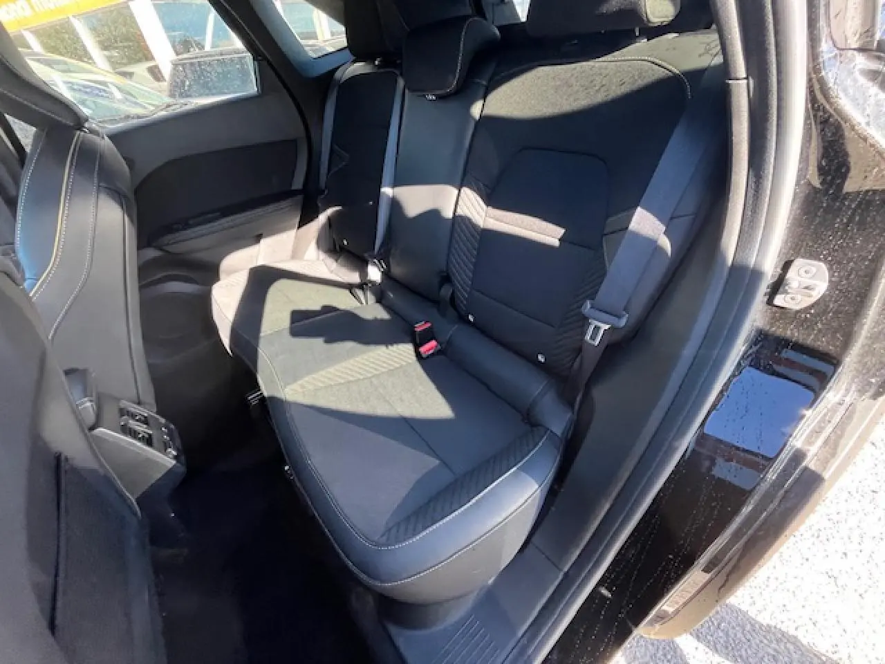 Vue intérieure côté droit sur la banquette arrière noire du Renault Symbioz 2025 avec porte ouverte et ceinture visible.