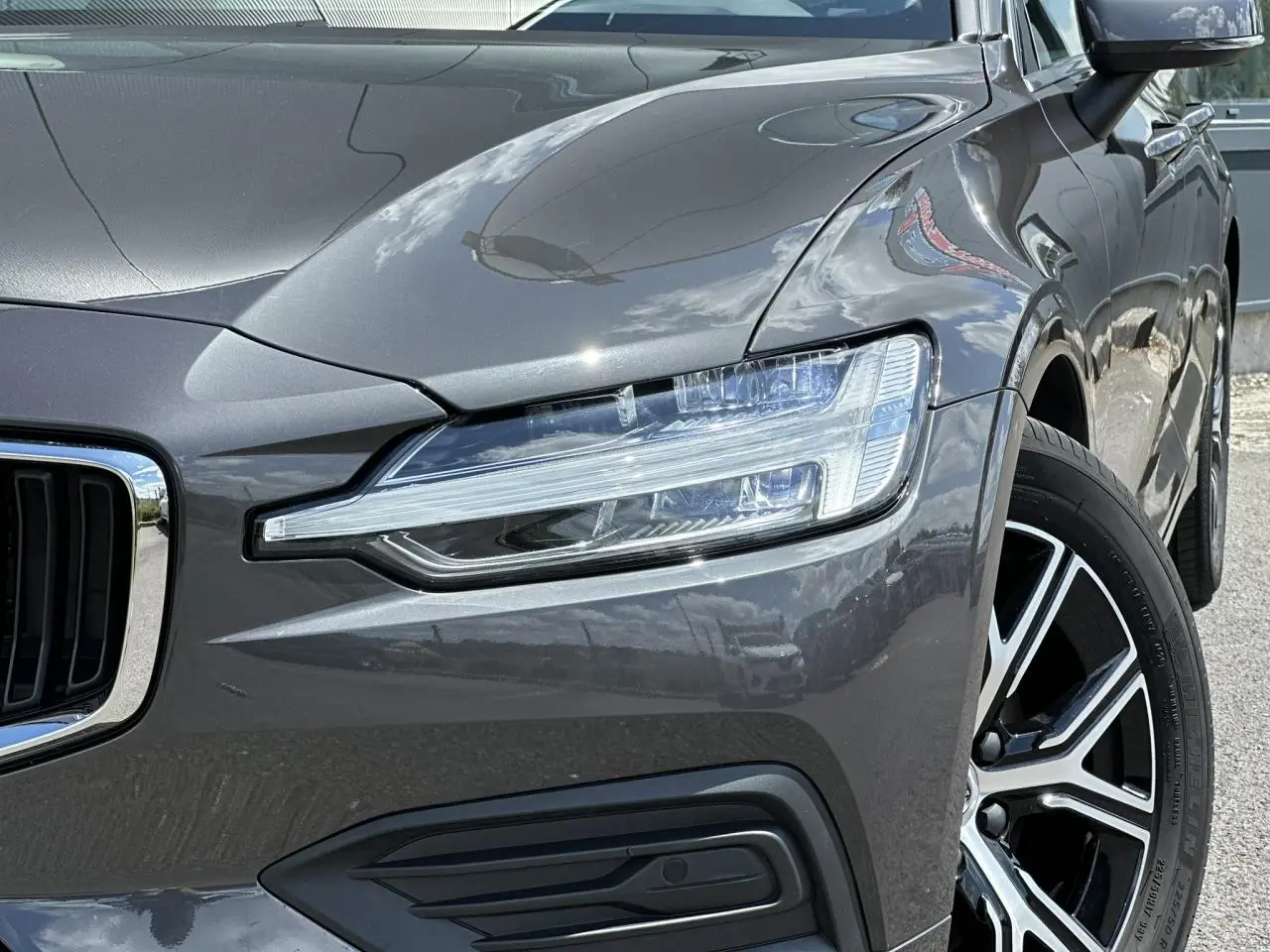 Gros plan sur l'avant droit d'une Volvo S60 gris Platinium, mettant en valeur le phare LED et la jante alliage 17 pouces.