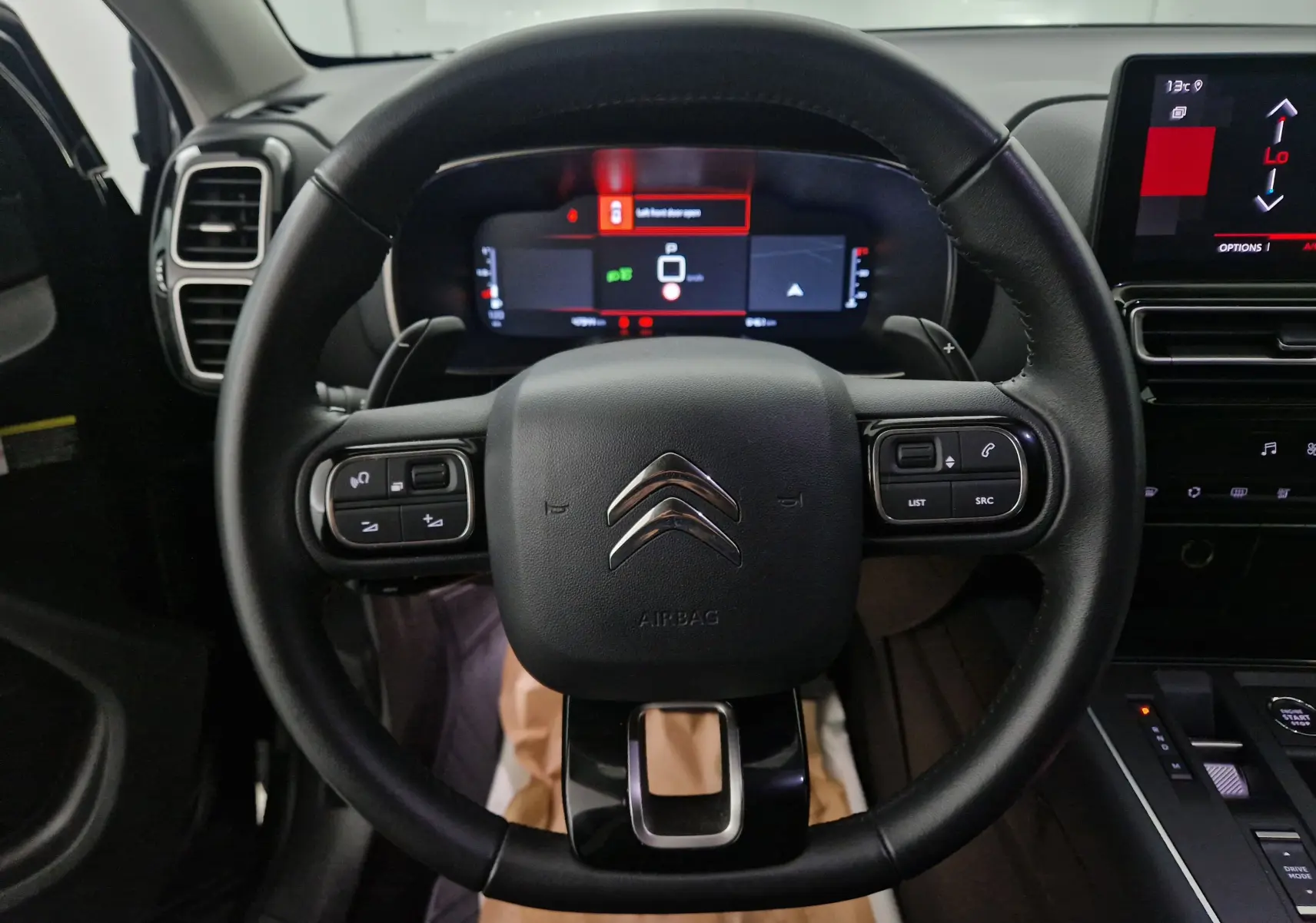 Vue rapprochée du volant noir de la Citroën C5 Aircross 2024 avec tableau de bord numérique et écran tactile central.