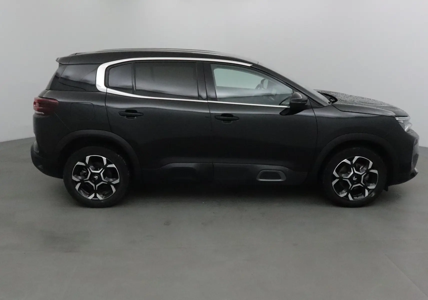 Profil côté gauche d'un Citroën C5 Aircross noir 2024 avec jantes alliage et lignes chromées distinctives.