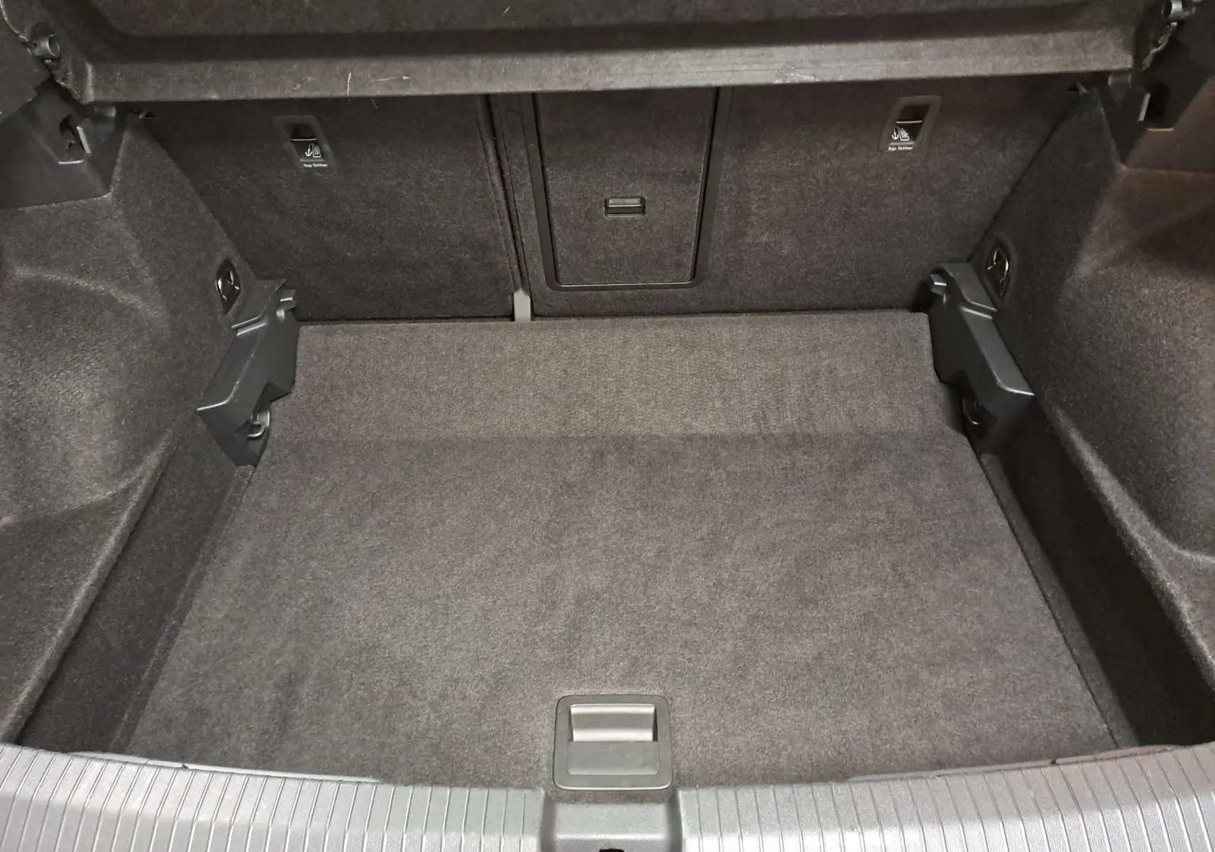 Coffre vide du Volkswagen T-Roc 2024, vue intérieure arrière, revêtement tissu gris foncé sans chargement visible.