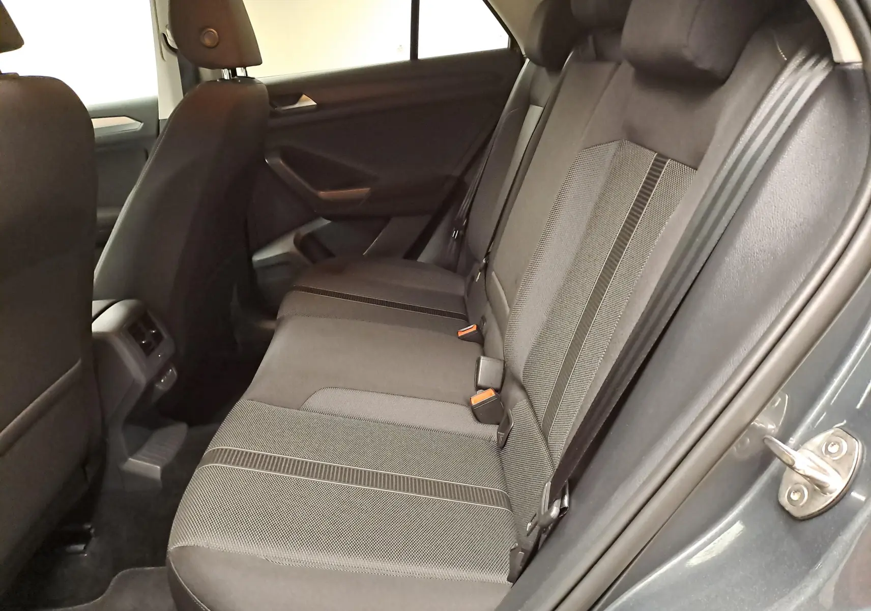 Vue intérieure côté droit des sièges arrière du Volkswagen T-Roc 1.5 TSI 150 DSG7 LIFE en gris Indium, tissu bicolore.