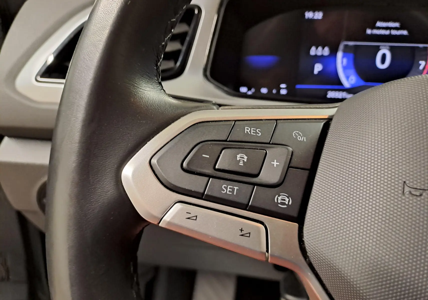 Gros plan sur les commandes de régulateur de vitesse au volant du Volkswagen T-Roc 2024, intérieur noir et gris.