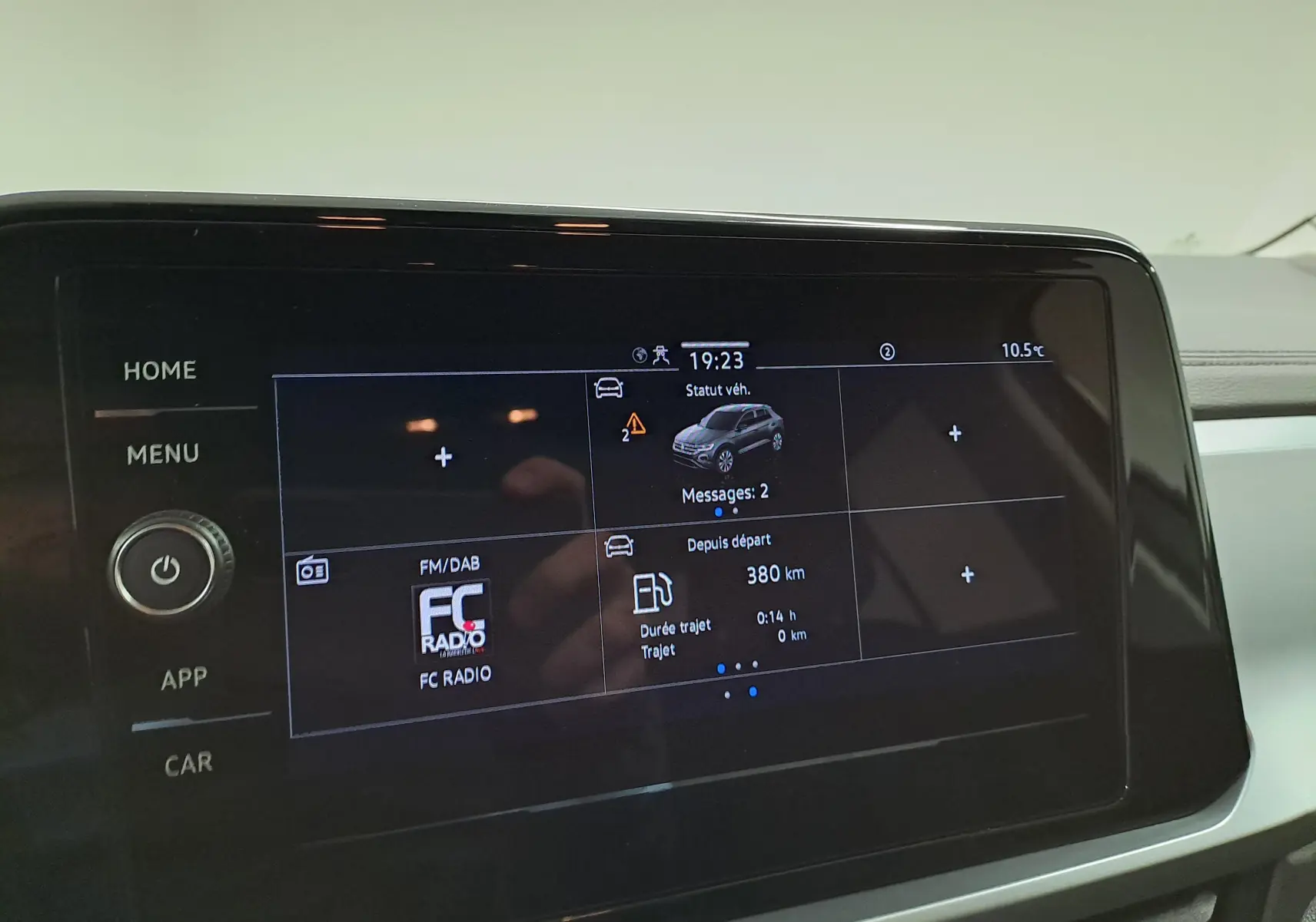 Écran tactile central du Volkswagen T-Roc 2024 affichant le statut véhicule et la radio FM, intérieur sobre et moderne.