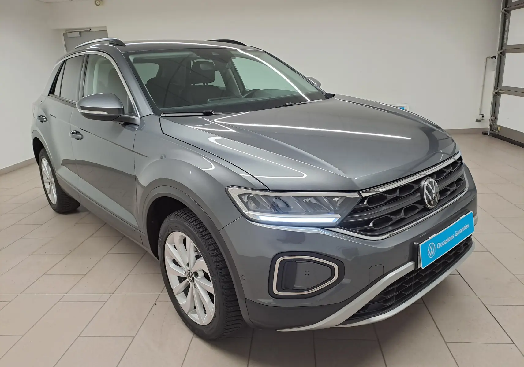 Volkswagen T-Roc 1.5 TSI gris Indium vu en 3/4 avant droit avec jantes alliage 17'' Johannesburg et feux LED allumés.