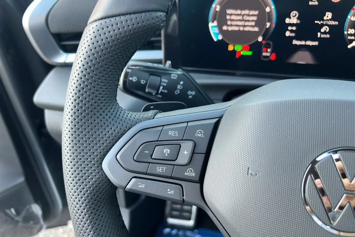 Gros plan sur le volant cuir perforé gris du Volkswagen T-Roc 2026 avec commandes multifonctions et tableau de bord numérique.