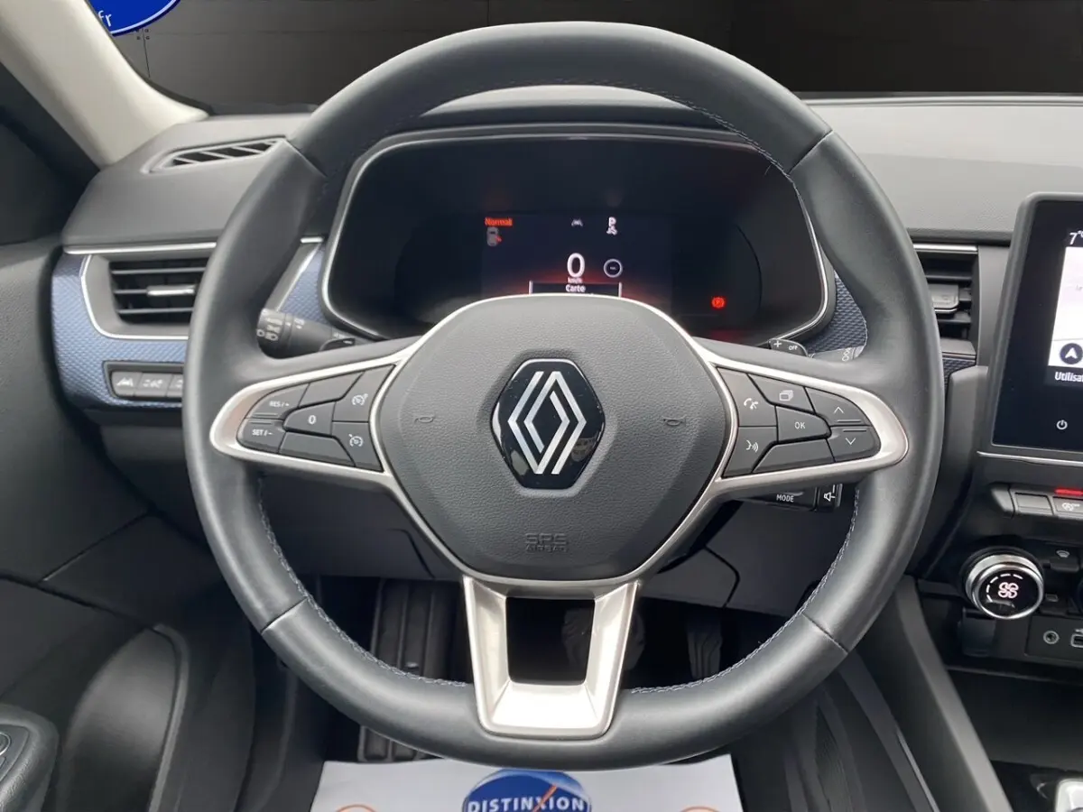 Vue centrée sur le volant cuir et aluminium du Renault Arkana 2024 avec tableau de bord numérique et écran tactile.