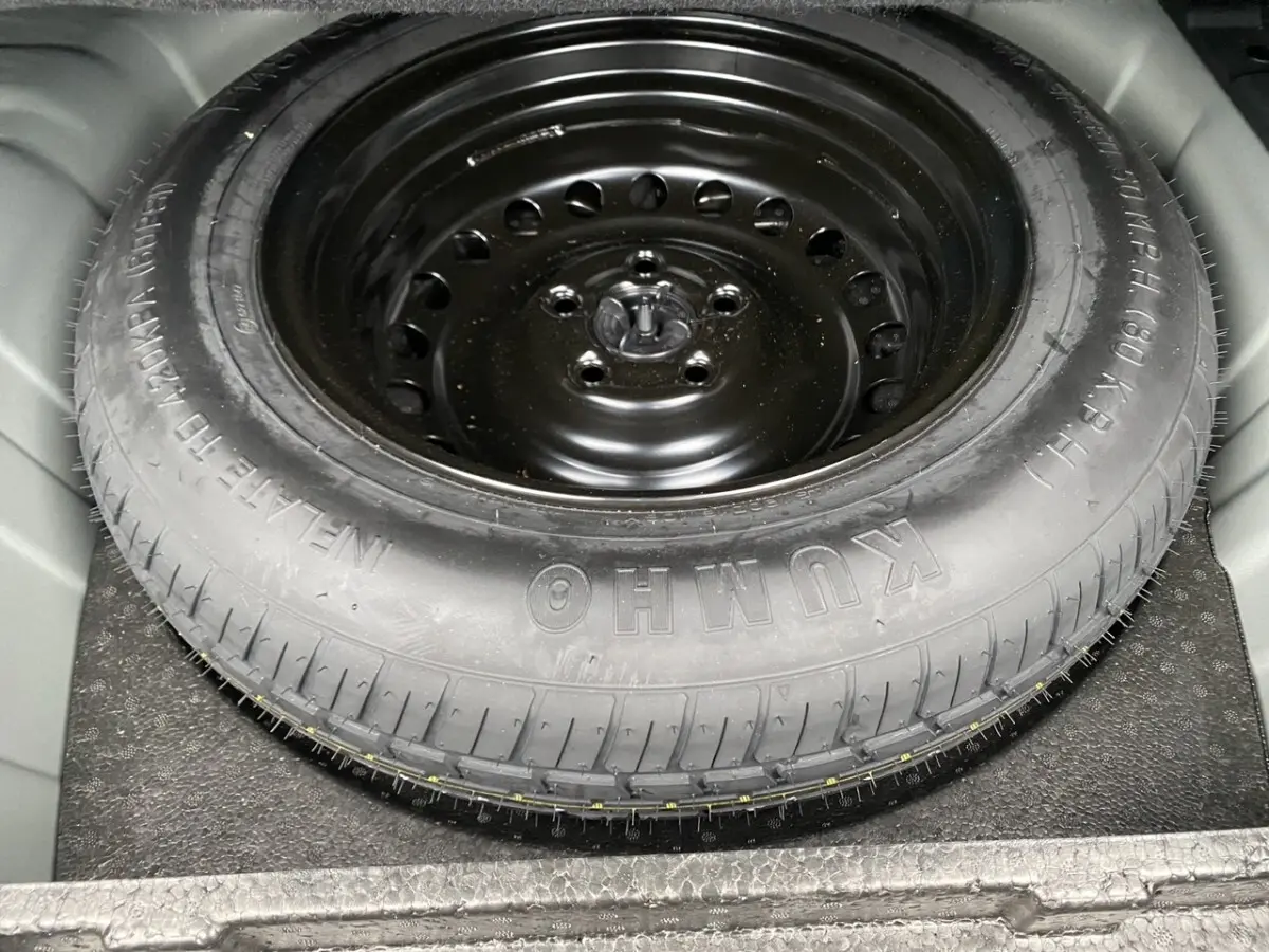 Gros plan sur la roue de secours noire en acier dans le coffre d’un Renault Arkana noir 2024.