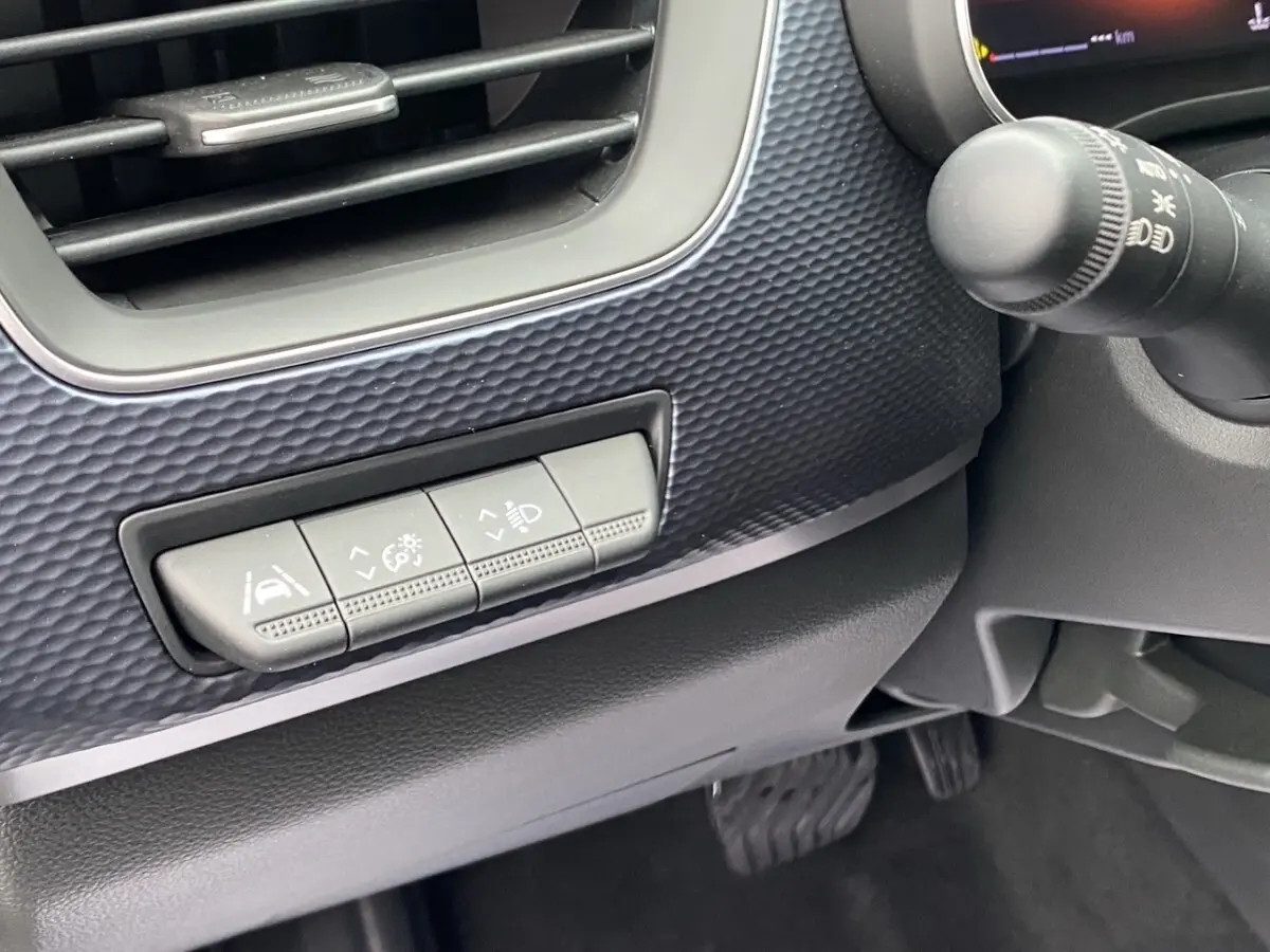 Détail intérieur côté gauche du tableau de bord noir du Renault Arkana 2024 avec boutons de réglage des aides à la conduite.