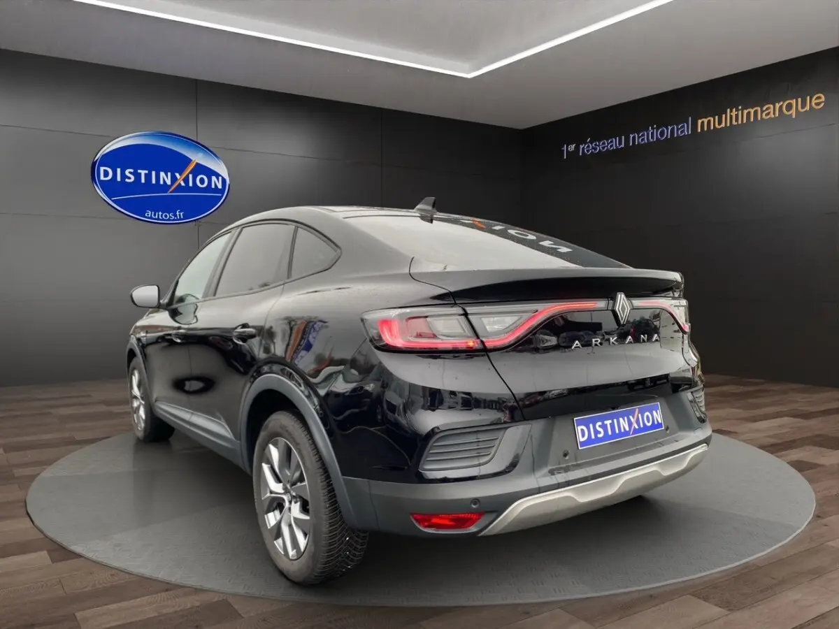 Vue 3/4 arrière droite du Renault Arkana noir 2024 avec feux arrière LED et logo distinctif sur fond showroom.