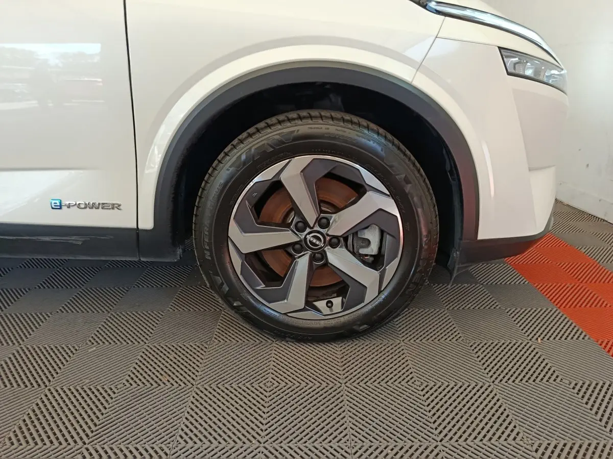 Gros plan sur la roue avant droite du Nissan Qashqai e-Power blanc avec logo e-Power sur la carrosserie.