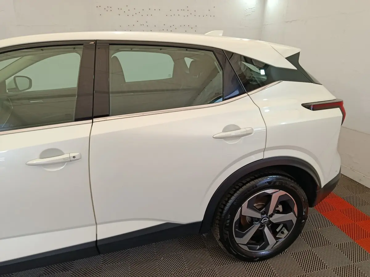 Vue latérale côté droit du Nissan Qashqai blanc 2024, mettant en valeur la roue arrière et les lignes épurées du SUV.