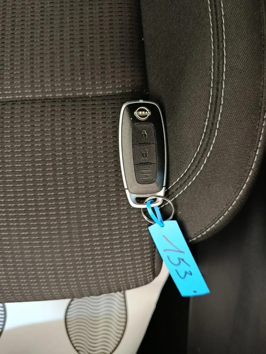Clé de voiture Nissan posée sur un siège tissu noir avec couture blanche, intérieur du Nissan Qashqai e-Power 2024.