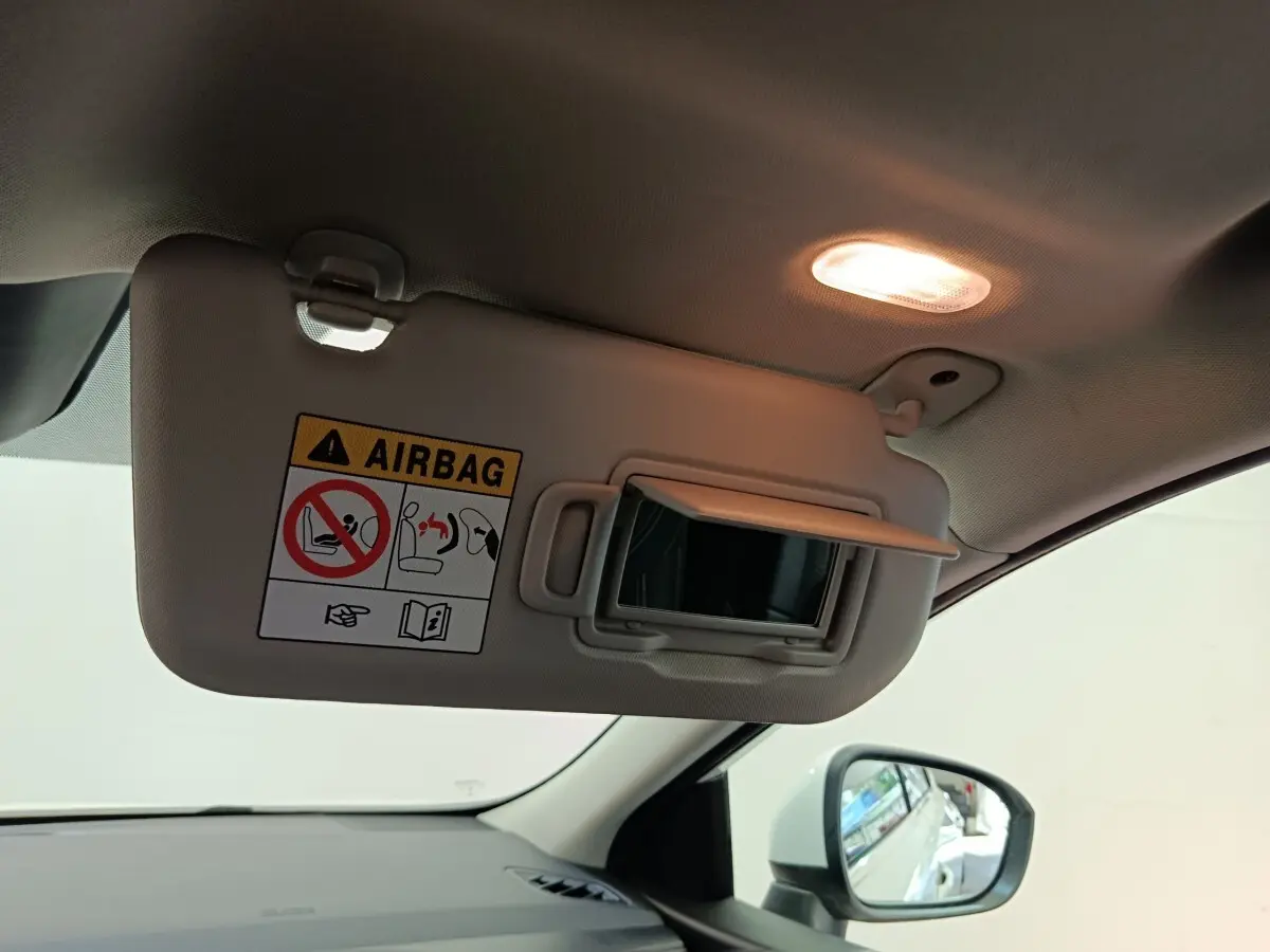 Pare-soleil côté conducteur beige avec miroir ouvert et lumière intérieure allumée dans un Nissan Qashqai blanc 2024.