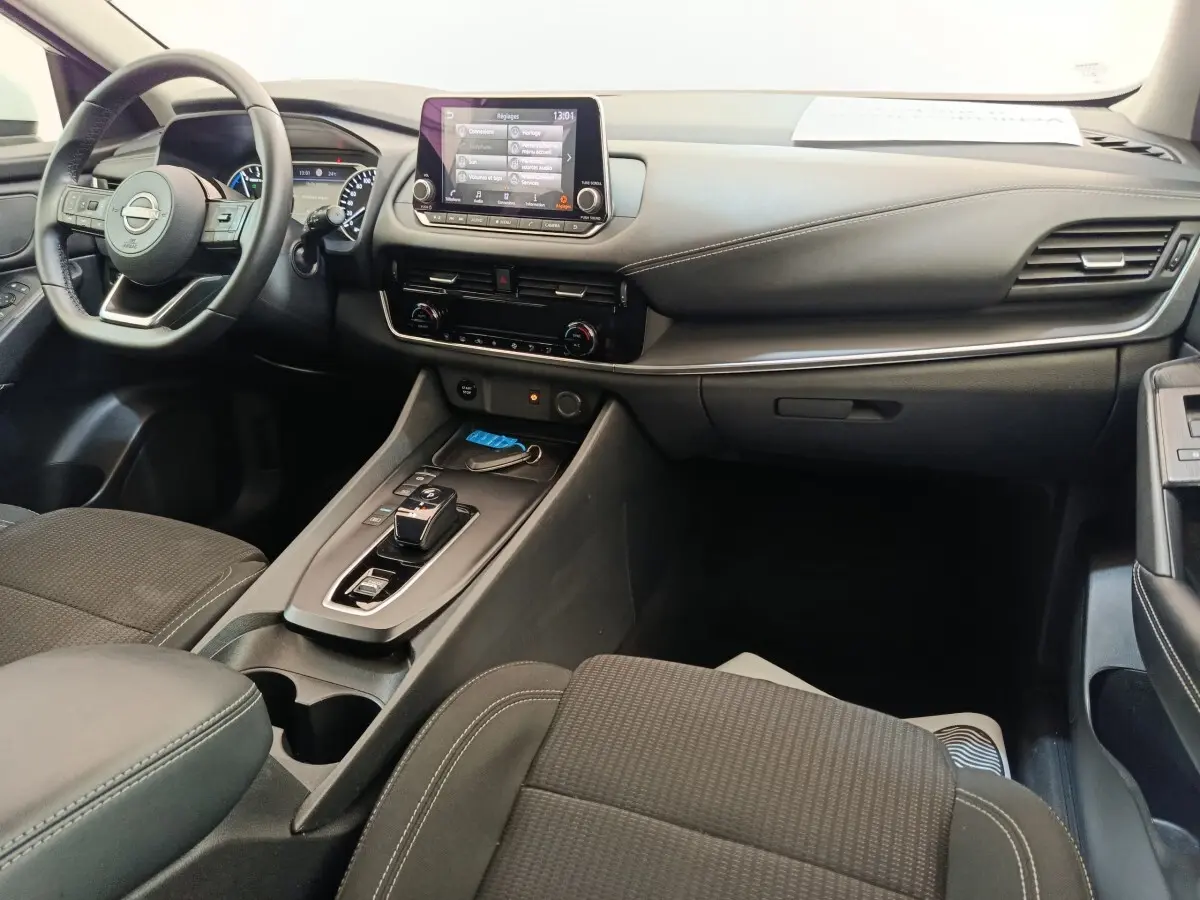 Intérieur noir du Nissan Qashqai e-Power 2024 vu côté passager, avec tableau de bord et écran tactile central.
