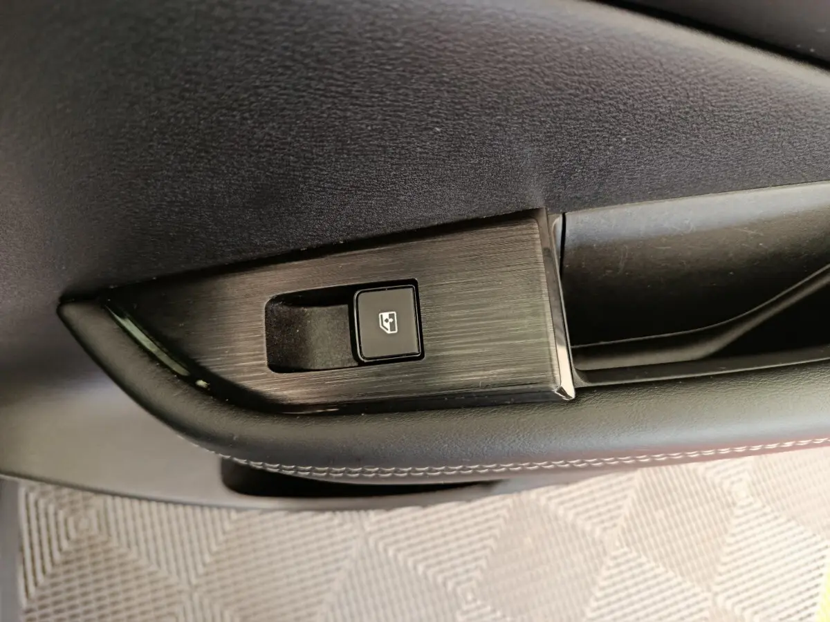 Gros plan sur le bouton de commande de la vitre électrique sur la porte intérieure noire du Nissan Qashqai e-Power 2024.