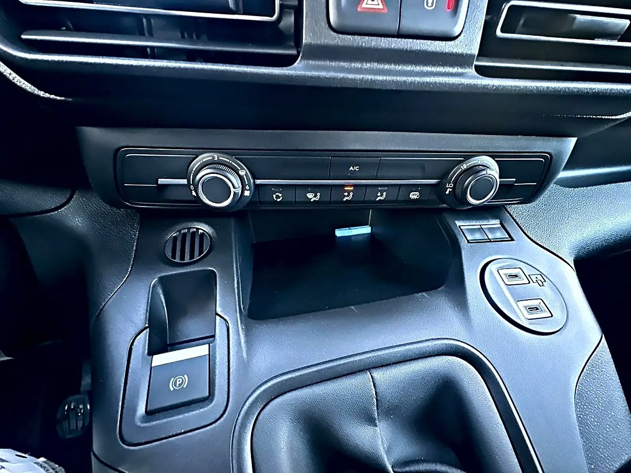 Détail de la console centrale noire du Citroën Berlingo Fourgon M diesel 100, avec commandes clim et prises USB visibles.