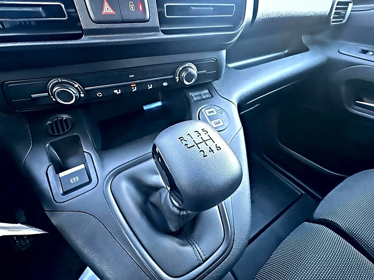 Gros plan sur le levier de vitesses manuel noir du Citroën Berlingo Fourgon blanc, avec tableau de bord et commandes visibles.