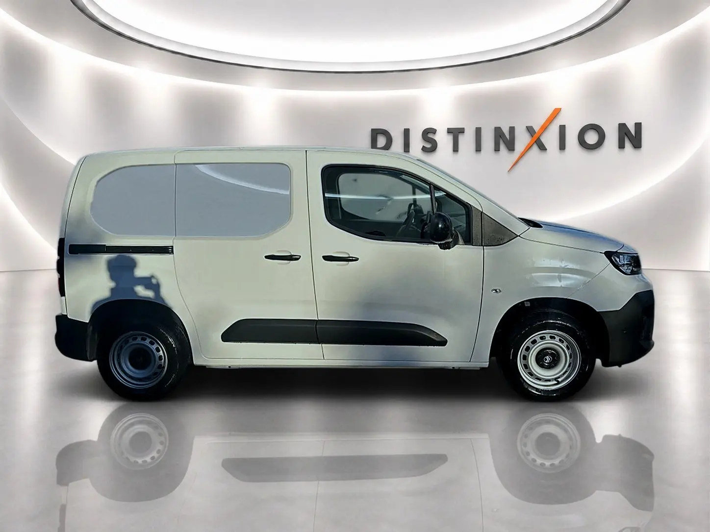Profil droit du Citroën Berlingo Fourgon blanc avec porte latérale coulissante, roues acier et logo Distinxion en arrière-plan.