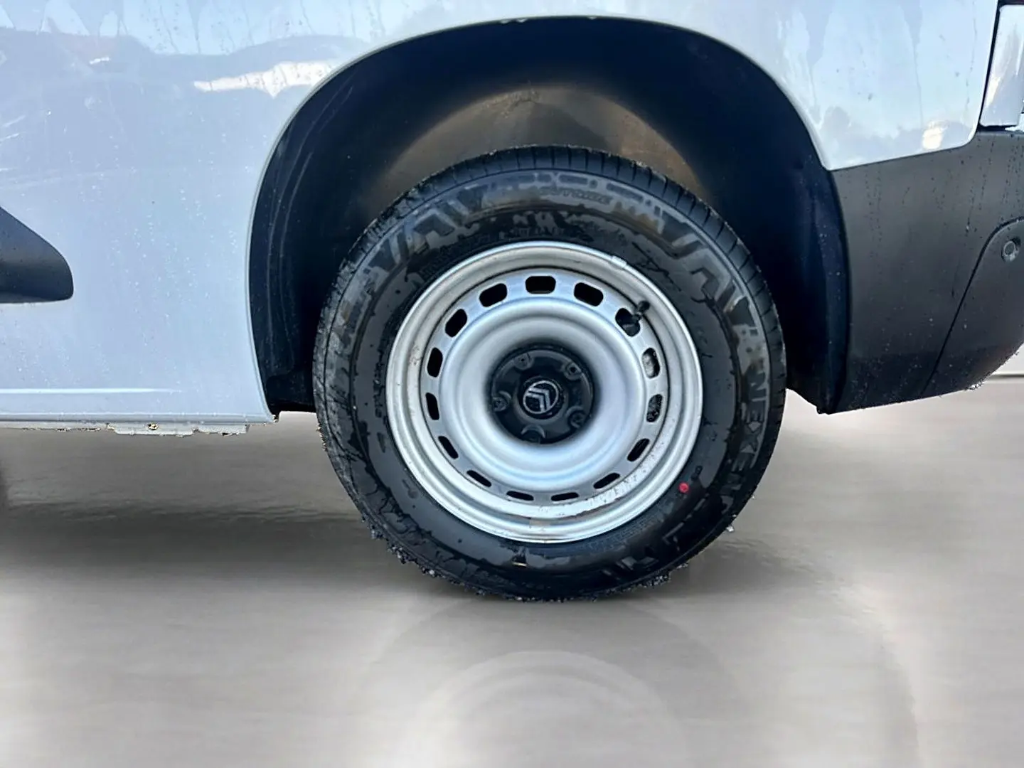 Gros plan sur la roue arrière droite blanche d’un Citroën Berlingo Fourgon M diesel 100, avec jante acier.