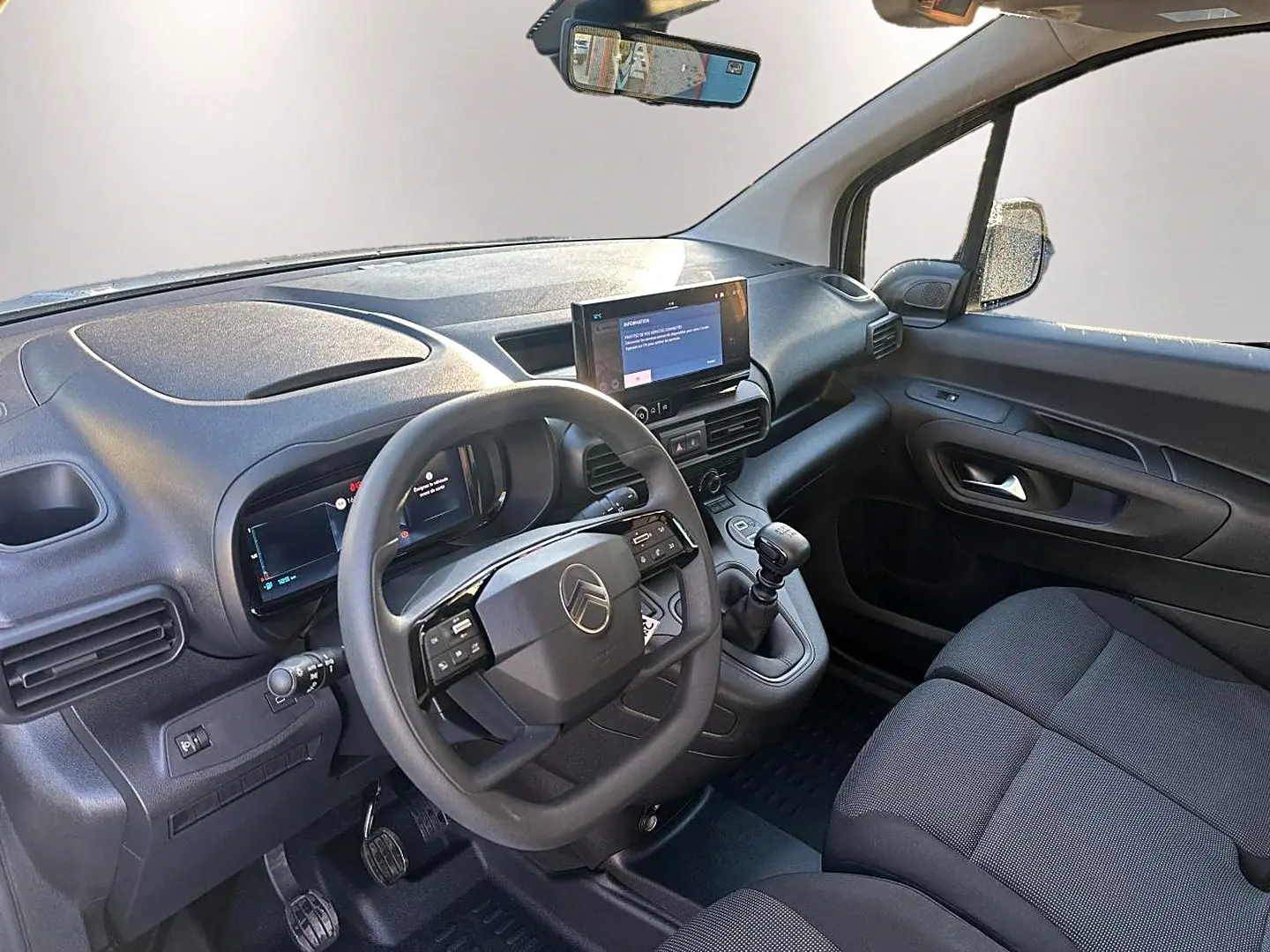 Vue intérieure côté conducteur du Citroën Berlingo Fourgon blanc, montrant le volant multifonction et la tablette tactile centrale.