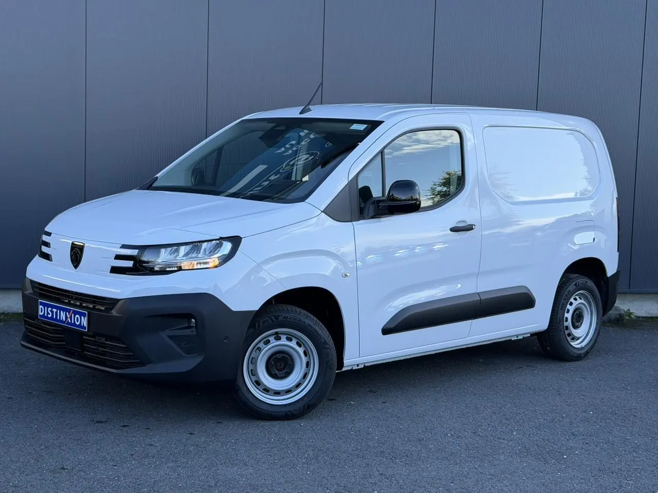 Peugeot Partner blanc Icy en 3/4 avant droit, avec rétroviseurs noirs brillants et protections latérales noires.
