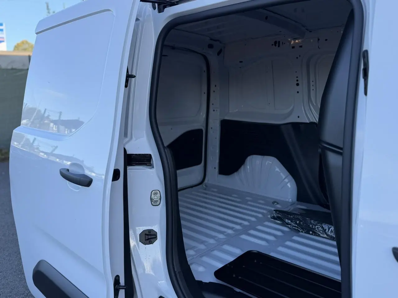 Vue latérale droite du Peugeot Partner blanc Icy 2026 avec porte coulissante ouverte sur l'espace de chargement vide.