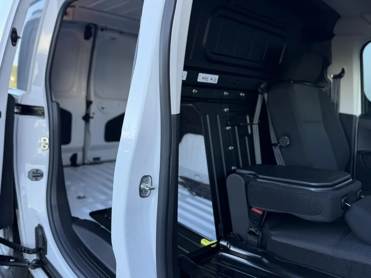 Vue intérieure côté droit du Peugeot Partner blanc Icy, montrant la cabine Extenso avec banquette passager rabattable.