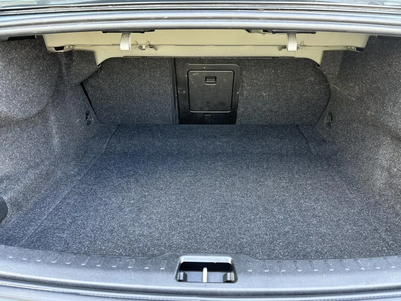 Coffre spacieux et vide de la Volvo S60 B4 2024 en gris Thunder, vue intérieure depuis l'arrière ouverte.