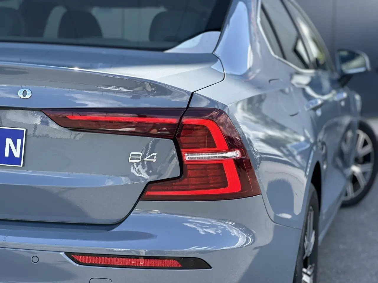 Vue arrière droite d'une Volvo S60 B4 gris Thunder avec feux LED et logo B4 visible sur le coffre