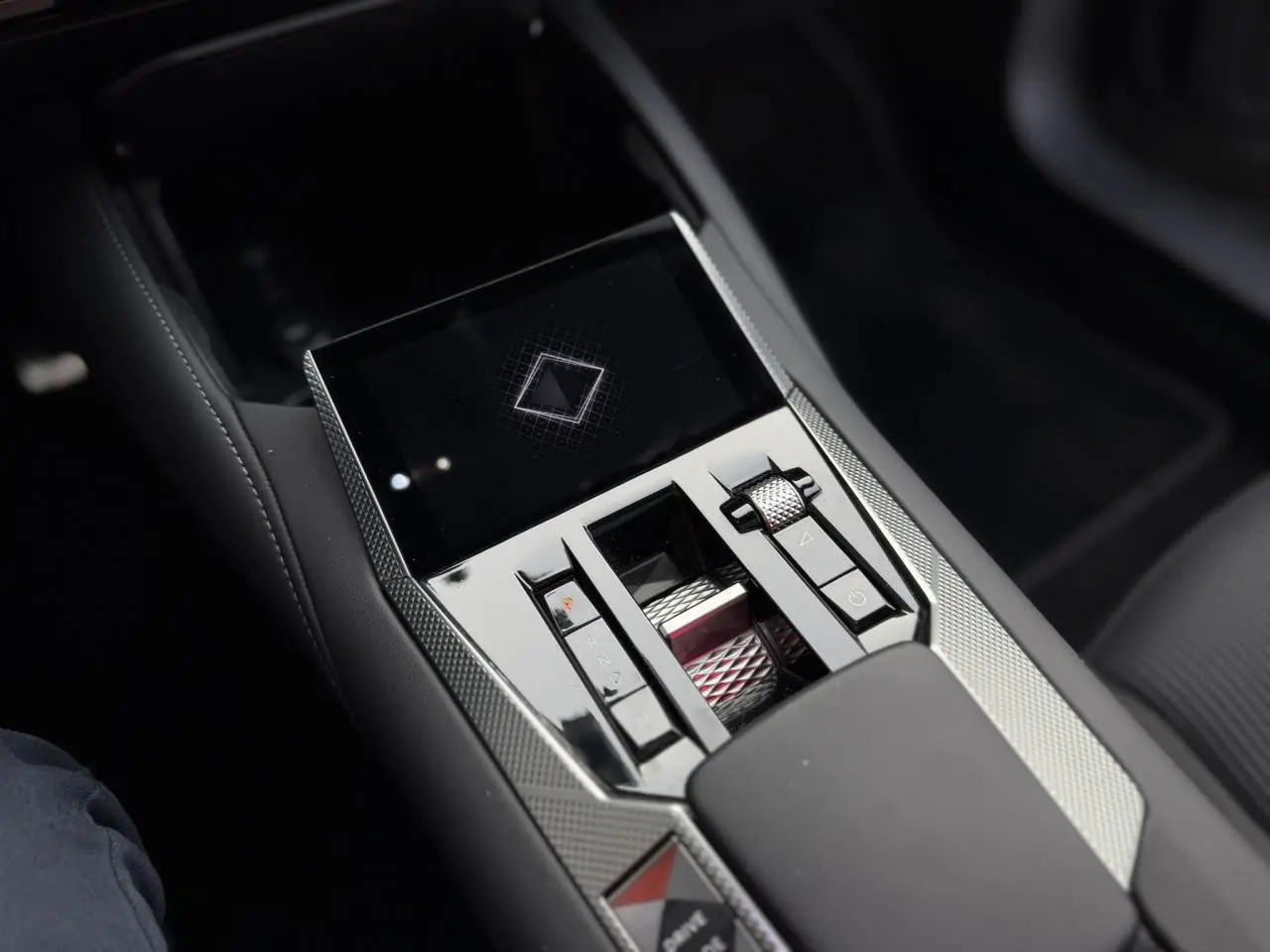 Gros plan sur la console centrale du DS4 2025, finition noire avec commandes tactiles et molette métallique texturée.