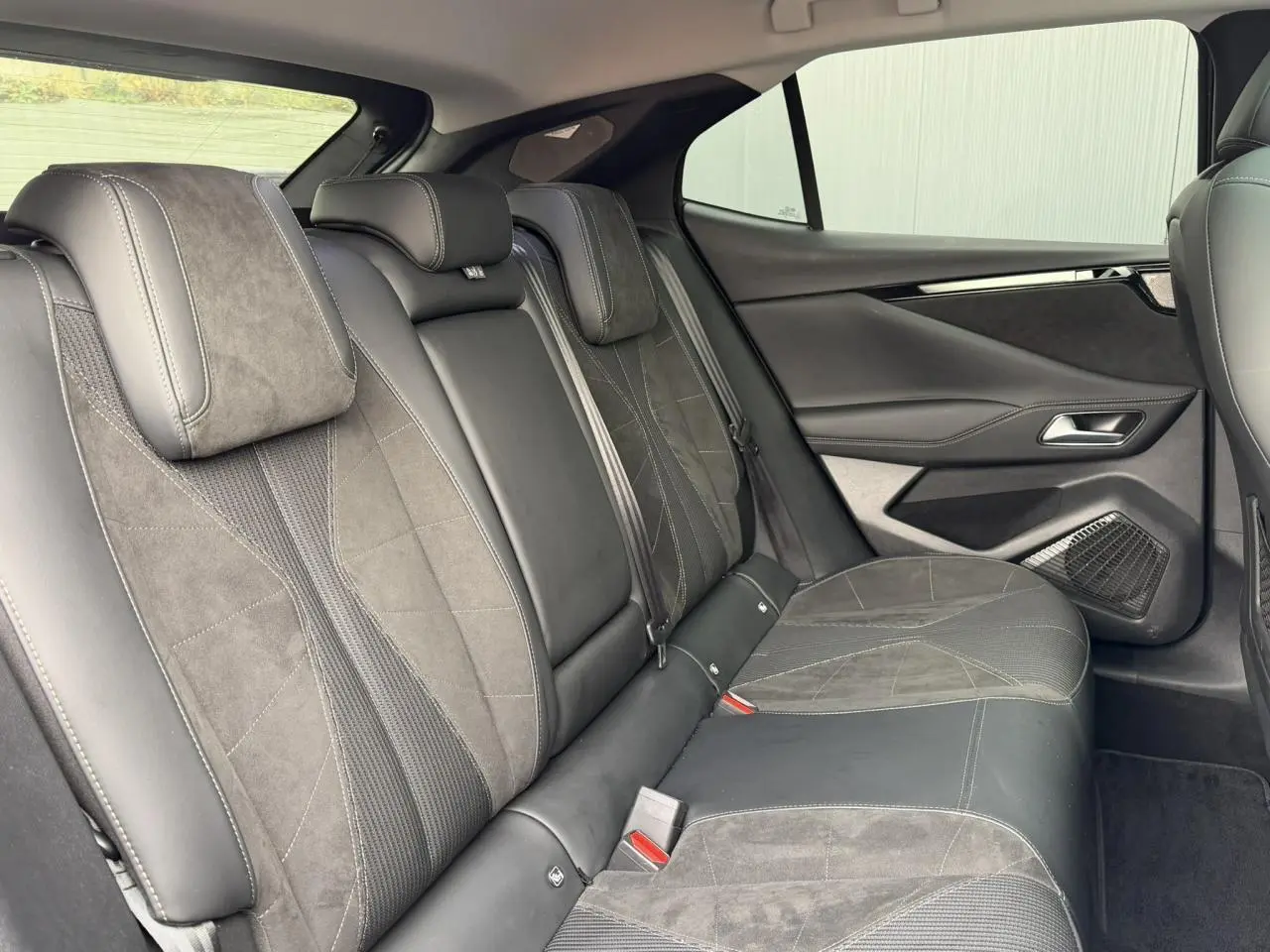 Vue intérieure des sièges arrière en Alcantara noir et tissu tressé sur DS4 2025, avec panneaux de porte assortis.