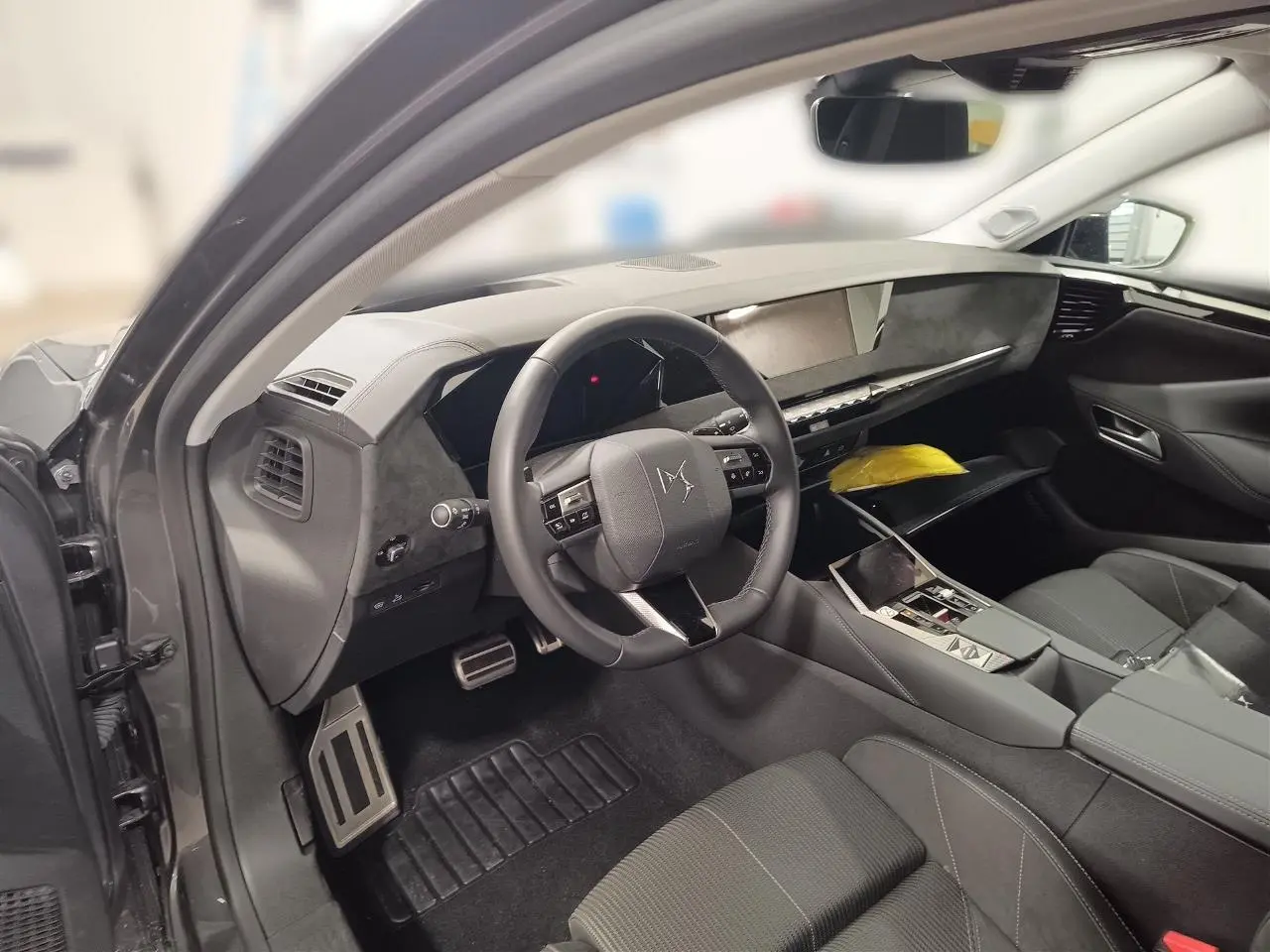 Intérieur avant gauche du DS4 2025 gris Platinium, volant cuir, planche de bord élégante et sièges tissu Alcantara.