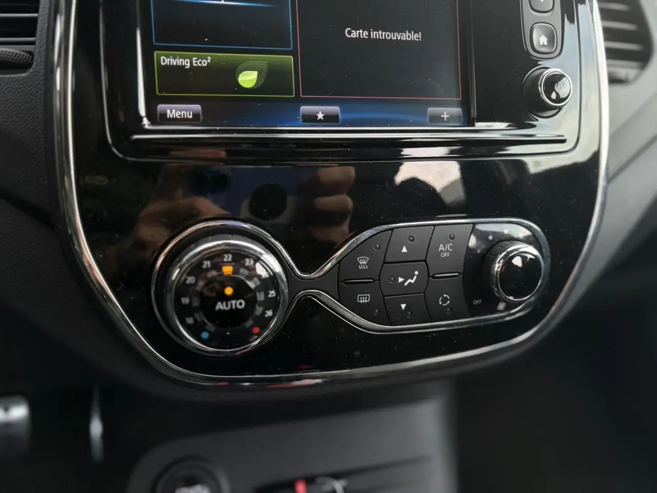Gros plan sur la console centrale noire brillante du Renault Captur 1.5 DCI avec écran tactile et commandes de climatisation.