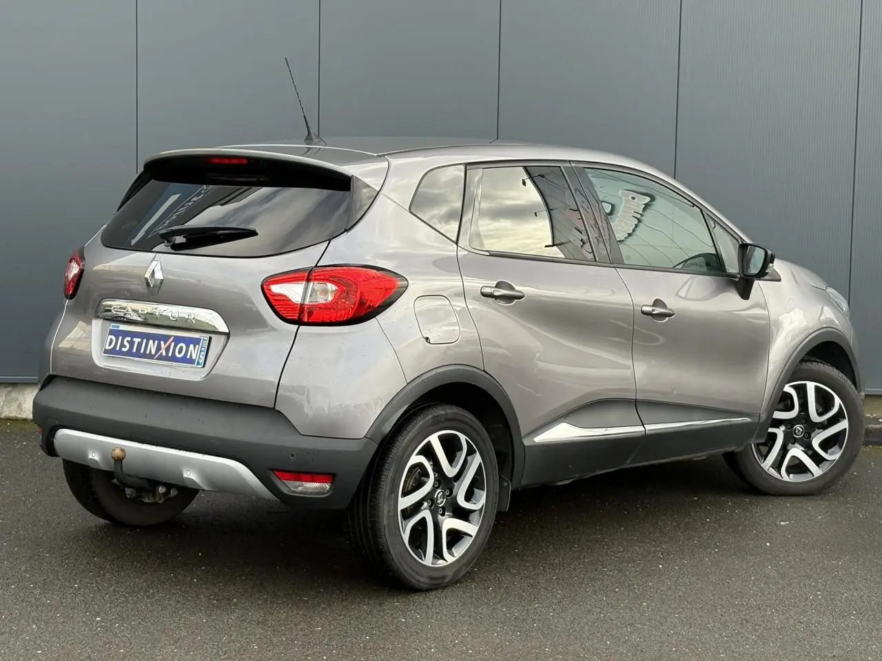 Vue 3/4 arrière droite d’un Renault Captur gris Cassiopée avec jantes alliage noires et vitres surteintées.
