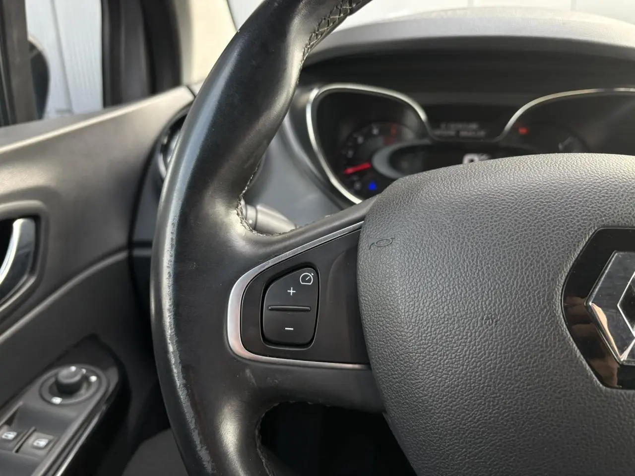 Gros plan sur le volant cuir noir du Renault Captur 2017, montrant les commandes de régulateur côté gauche.