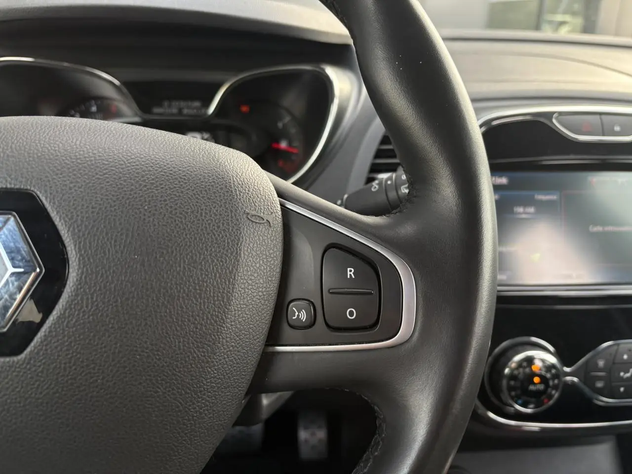 Gros plan sur le volant cuir noir du Renault Captur 2017 avec commandes intégrées et écran tactile du système multimédia.